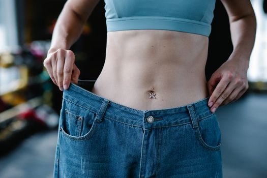 woman measuring waist belly fat reduction before after