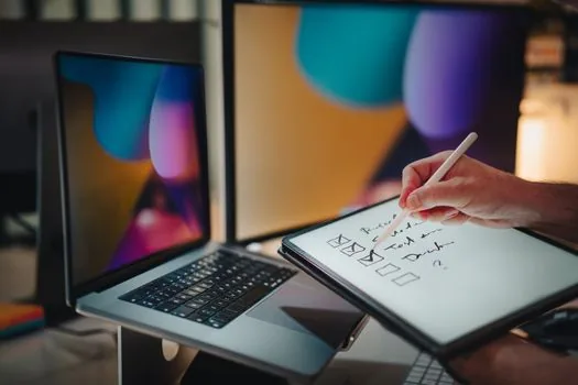 person checking task manager and PDF reader troubleshooting checklist on Windows laptop
