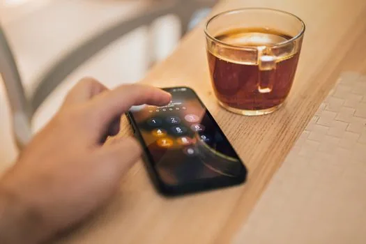 person writing down backup password hint beside smartphone chat settings screen, no visible real app logo, bright realistic photo | 대화 백업 비밀번호를 잊지 않게 따로 정리하는 장면