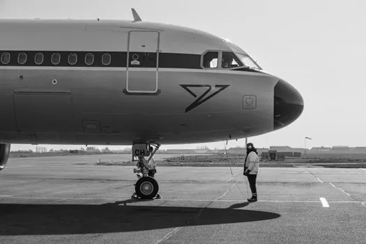 Airline ground staff checking luggage cart near aircraft loading area, delayed departure situation, realistic airport operations photo