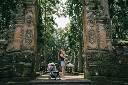 bright Bali neighborhood street with family travel bags near villa entrance, tropical plants, editorial lifestyle photo, no readable signs | 발리 현지 생활을 시작하는 가족 이주 이미지