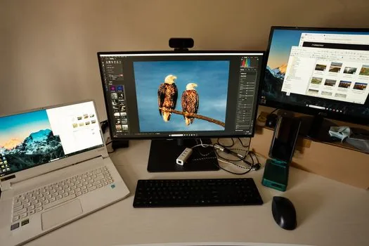 desktop monitor showing messenger download page with smartphone beside keyboard, bright Korean home desk