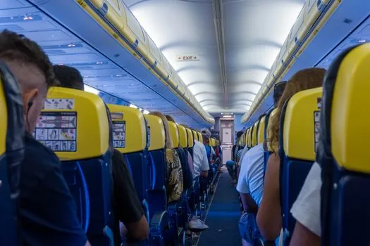 Family passengers seated in airplane cabin with cabin crew assisting calmly, no celebrity likeness, respectful documentary travel photo