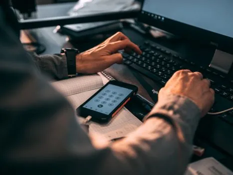 Korean office worker checking fax number on phone before sending certificate