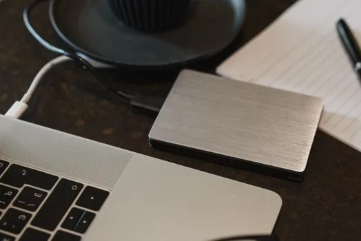 Korean user organizing iCloud photo originals on Windows laptop with external SSD and iPhone nearby, realistic bright desk, no logos, no readable private text | PC와 외장 SSD에 사진 원본을 정리하는 장면
