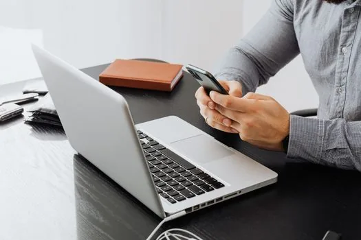 Korean user reviewing group admin settings before deleting messenger account, laptop and phone on tidy desk, realistic documentary lighting