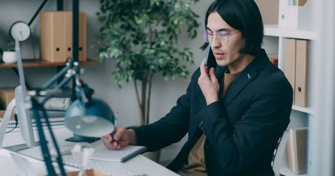 Korean user writing down repeated marketing call numbers and call times beside smartphone call log, calm bright desk, no private numbers visible | 광고전화 번호와 통화 시간을 증빙용으로 정리하는 장면