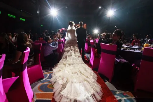wedding venue staff politely showing a dress code sign near entrance, guests in formal attire, warm documentary lighting, no faces emphasized | 예식장 입구에서 복장 안내를 확인하는 하객 장면