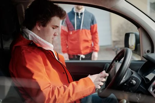 Korean driver checking inspection reservation result and cancellation screen on smartphone beside car keys and garage appointment memo, realistic editorial photo