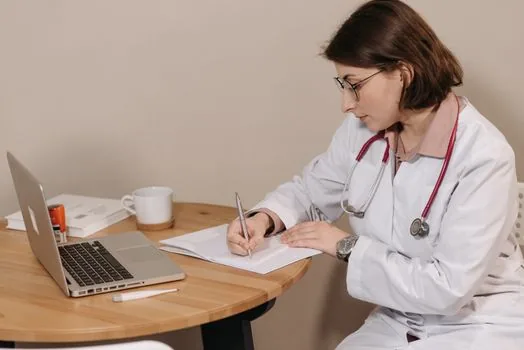 Korean job applicant reviewing national health checkup history on laptop with medical papers and ID card on bright desk | 국가건강검진 이력과 직장 제출 서류를 확인하는 장면