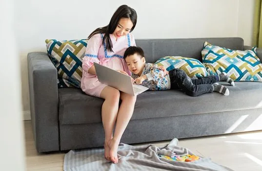 Korean parent checking Government24 Happy Birth integrated application on laptop with birth certificate and bankbook, realistic bright home desk | 출생신고 뒤 행복출산 통합신청으로 아동수당을 확인하는 장면