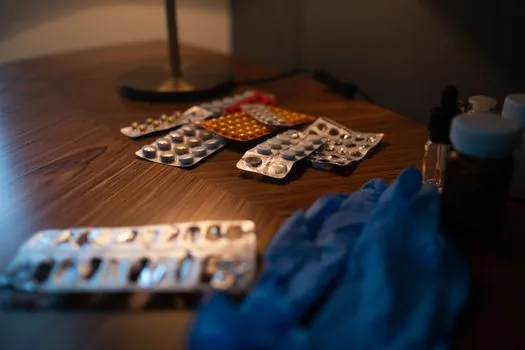Korean person sorting expired pills, powder medicine packets, syrup bottle and ointment on a kitchen table with paper envelope labeled 폐의약품 | 집에 남은 약을 종류별로 나눠 정리하는 장면