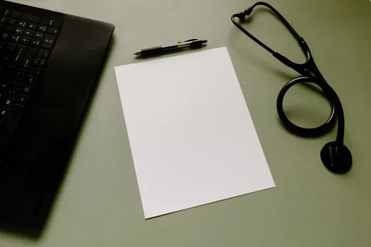 Korean public health insurance website login and employment document checklist on laptop, company submission memo beside keyboard | 국민건강보험공단 로그인과 제출처 입력을 준비하는 장면