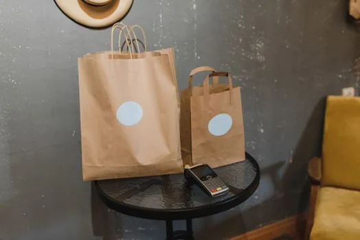 Korean shopper checking mobile receipt setting in department store app before payment, reusable shopping bag on counter, realistic photo