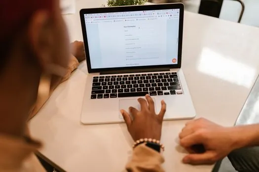 laptop showing online civil service application beside identity card and printer, local tax certificate preparation scene, no readable personal data