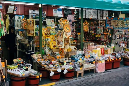 a quiet Tokyo fabric shop street with colorful folded textiles seen from outside, early afternoon natural light, travel magazine editorial photography, no signs readable