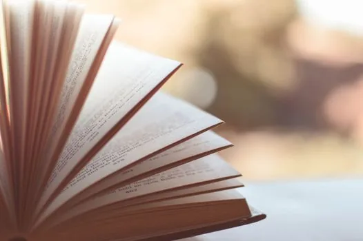 a travel notebook open beside a coffee cup with airport departure board blurred in the background, calm documentary style, shallow depth of field, no readable text