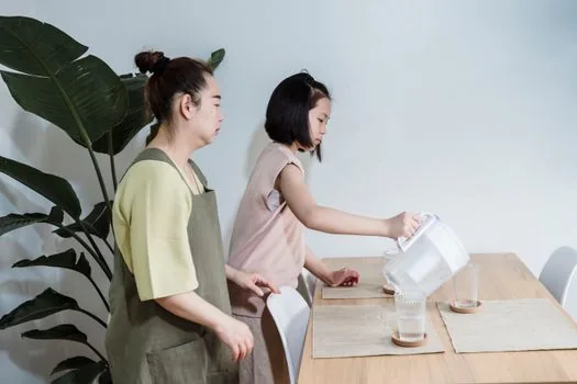 child drinking water slowly while parent checks mouth discomfort and hydration memo, bright home care scene, realistic photo | 입안 통증과 수분 섭취를 확인하는 장면