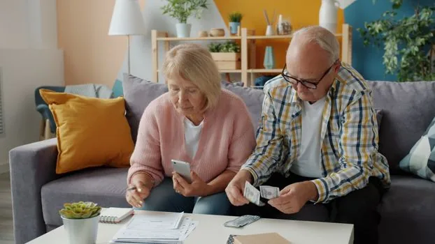 family meeting about senior town move, tax bill, health insurance memo, housing pension note and monthly budget sheet on table