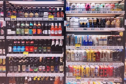 convenience store drink refrigerator with customer comparing beverage price labels, realistic Korean retail scene, no visible brand logos | 편의점 음료 매대에서 가격표를 비교하는 장면