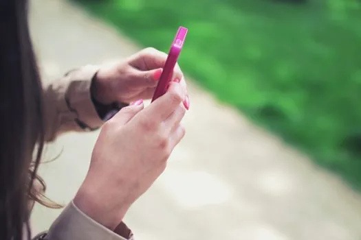Korean adult checking pickup notification on smartphone outside local community service center, ID photo envelope and checklist in hand, realistic editorial photography, no readable text