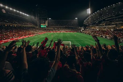 Korean football fans checking match score and coach debate on phones outside stadium after night game, realistic editorial photo | 경기 직후 팬들이 스코어와 감독 논란을 함께 확인하는 장면