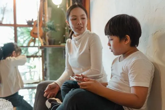 Korean parent comparing hide and unsubscribe options on calendar settings screen with family schedule notes nearby, realistic daylight table | 숨김과 구독 취소를 비교해 선택하는 장면