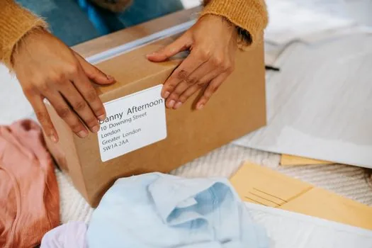 Korean person measuring parcel box at apartment doorway before post office pickup booking, realistic practical guide photo | 방문접수소포 예약 전 박스 크기를 재는 장면