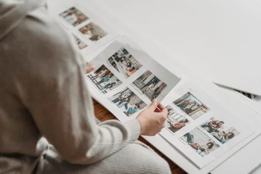 Korean user reviewing iPhone shared album participants at bright home table with printed family photos nearby | 아이폰 공유 앨범 참여자와 가족 사진을 함께 확인하는 장면