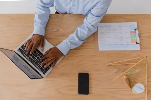 Korean user reviewing shared folder member list and permission levels on laptop, smartphone notes beside keyboard, realistic daylight workspace | MYBOX 멤버 초대 권한을 확인하는 장면