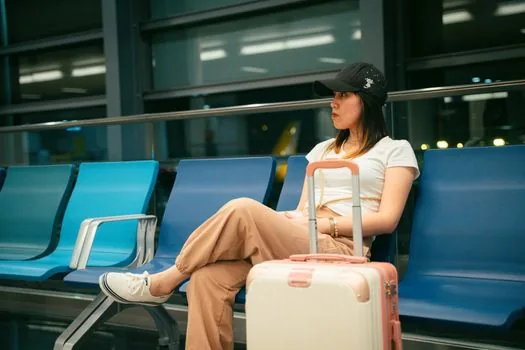 late night airport limousine bus stop with illuminated timetable and traveler waiting with suitcase, realistic terminal scene | 심야 공항버스 시간표와 탑승 날짜를 확인하는 장면
