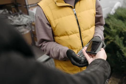 person reviewing recurring payment on smartphone beside delivery box, Korean apartment entryway, realistic photo, no brand logo | 자동결제 내역 확인 장면 | 결제일과 멤버십 상태를 먼저 확인하는 상황