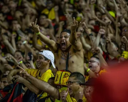 Vietnamese football fans celebrating after night match outside Hanoi stadium, red shirts, realistic editorial sports photo | 베트남 축구 우승 뒤 팬 관심이 다시 커진 장면