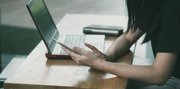 young Korean adult typing school record search query on official government service laptop, smartphone authentication beside keyboard, clean desk, documentary photo style