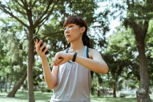 Korean adult checking health checkup result and smartphone health insurance app participation screen at home desk realistic photo | 건강검진 결과지와 The건강보험 앱 신청 화면을 함께 확인하는 장면