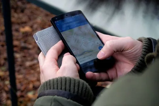 Korean adult searching night clinic and pharmacy on smartphone map outside apartment entrance, realistic photo, calm health information mood, no readable text