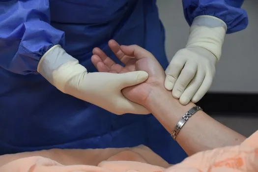 Korean adult sitting safely on clinic hallway chair after dizziness, nurse checking condition, realistic health editorial photo, no text | 어지럼 뒤 안전하게 앉아 상태를 확인하는 장면