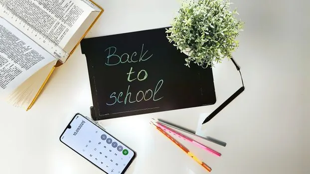 Korean high school applicant organizing admission application number, phone, calendar, and laptop on bright study desk, no real university logos