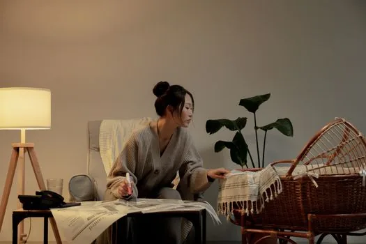 Korean parent calling maternity hospital while checking birth certificate and laptop application page, newborn items on clean desk, realistic photo | 온라인 출생신고 전 참여병원 여부를 확인하는 장면