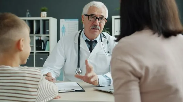 Korean parent checking toddler health checkup period on laptop and phone with appointment calendar, bright clinic desk, realistic no logos | 영유아 건강검진 대상 기간과 예약 가능일을 확인하는 장면