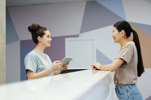 Korean patient at university hospital reception reviewing payment notice and referral letter checklist, bright hospital lobby, realistic editorial photo | 상급종합병원 접수 전 의뢰서와 본인부담을 확인하는 장면