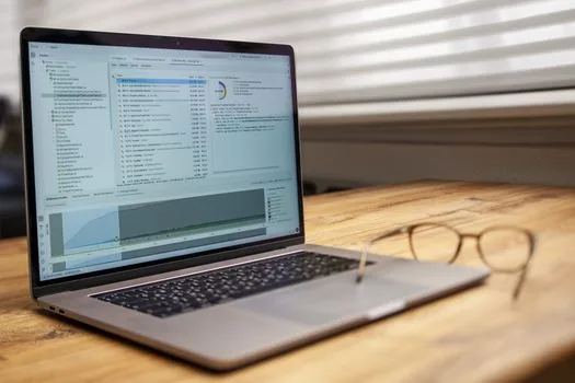 laptop screen showing generic online public service application checklist with wage slips and medical documents, clean bright desk, no readable personal data