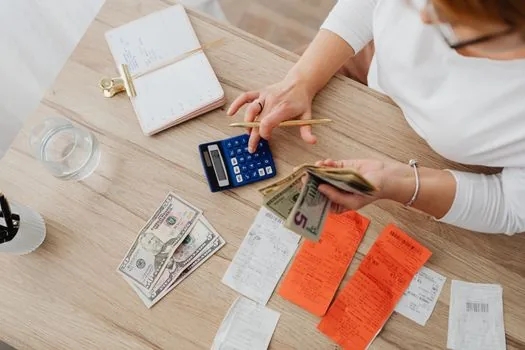 monthly rent receipt, maintenance fee statement, calculator and support amount memo on desk | 월세와 관리비를 나눠 지원 가능 금액을 확인하는 장면