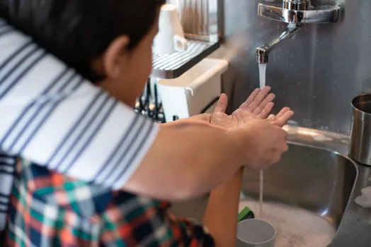 parent washing child's hands with soap near cleaned toys and separate cup, Korean home hygiene scene, realistic photo | 손씻기와 장난감 소독을 하는 장면