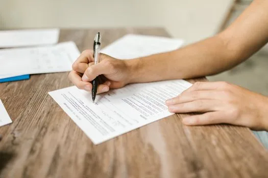 young Korean renter organizing lease contract, rent transfer records, resident registration document on small studio desk | 청년월세 지원사업 신청 전 임대차계약서와 월세 이체내역을 정리하는 장면