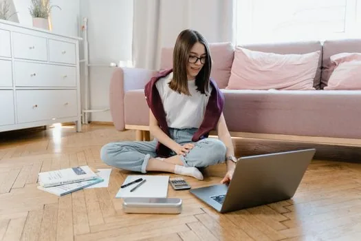 young renter comparing personal income papers and family household checklist on laptop, calm bright room | 청년가구와 원가구 기준을 나눠 확인하는 장면