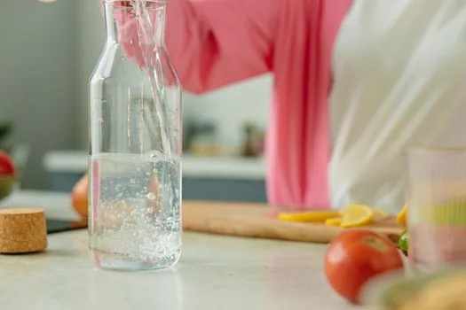 Close-up of clean restaurant water purifier nozzle and reusable bottle held below without touching | 정수기 추출구에 물통 입구가 닿지 않게 받는 위생 장면