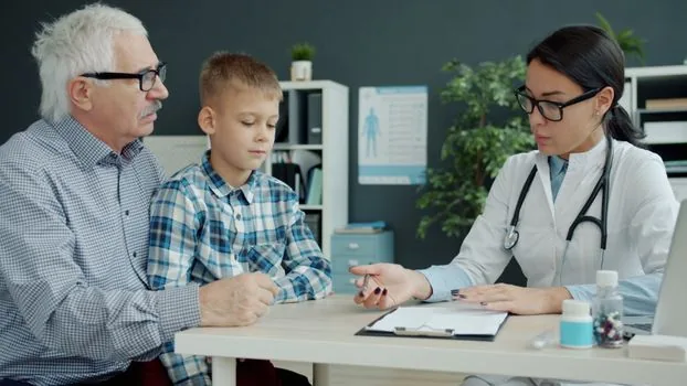 Korean parent and teenager reviewing vaccination schedule and student ID at clinic reception desk, bright health guide editorial photo, no readable personal data